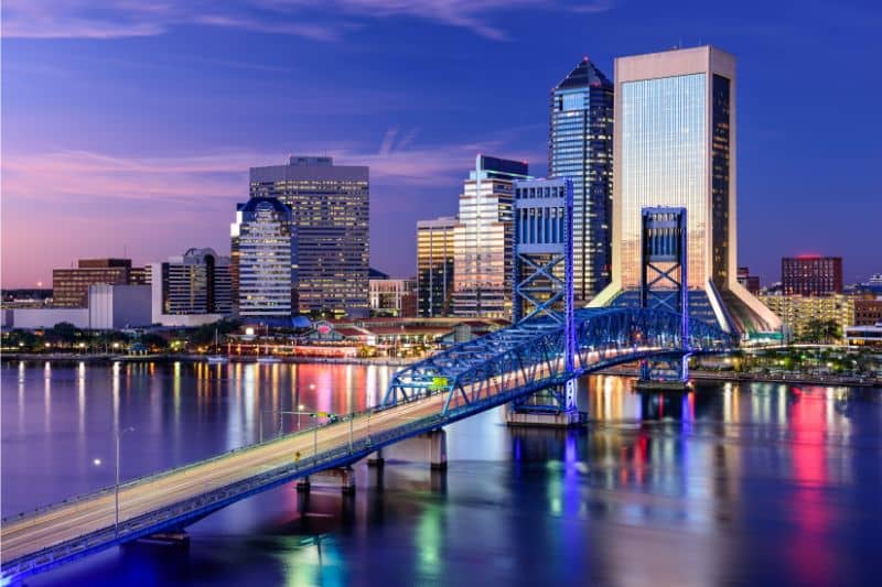 Jacksonville Florida downtown skyline with river bridge at sunset reflecting city lights on the water, representing local land surveying services