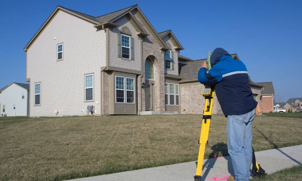 Land surveyor measuring a residential property during a boundary survey