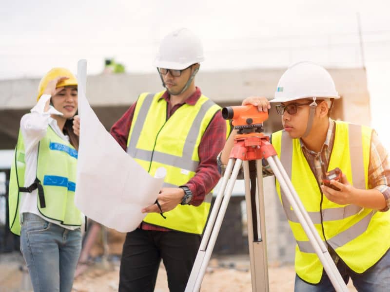 Surveying companies reviewing site plans and measuring land before commercial site development