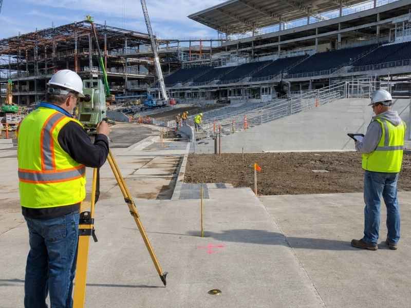 Land surveying for a major stadium improvement project in Jacksonville, Florida, with surveyors setting control points near seating and construction areas.