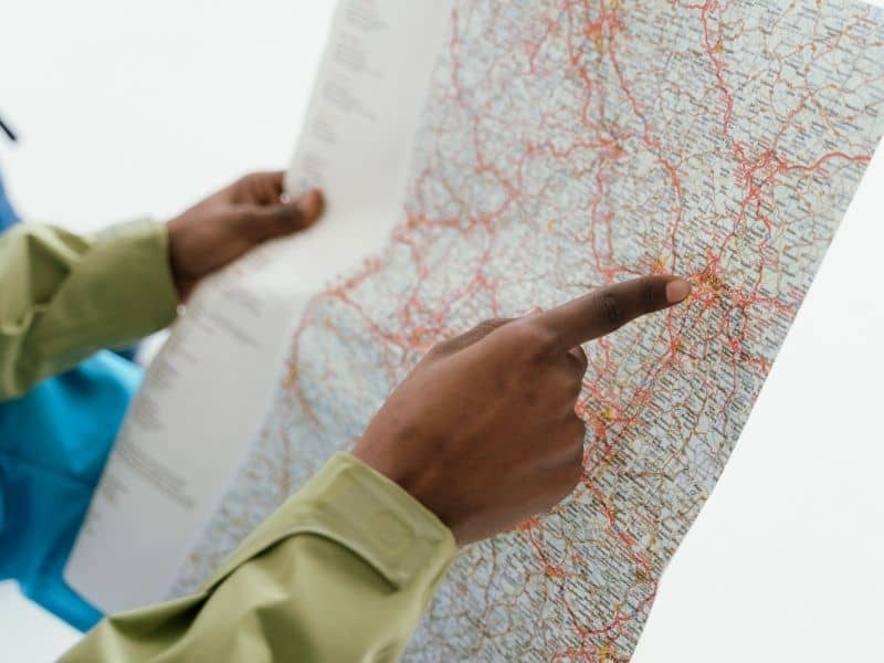 Two people study a large map, one pointing to a location with his finger used for navigation or planning travel.